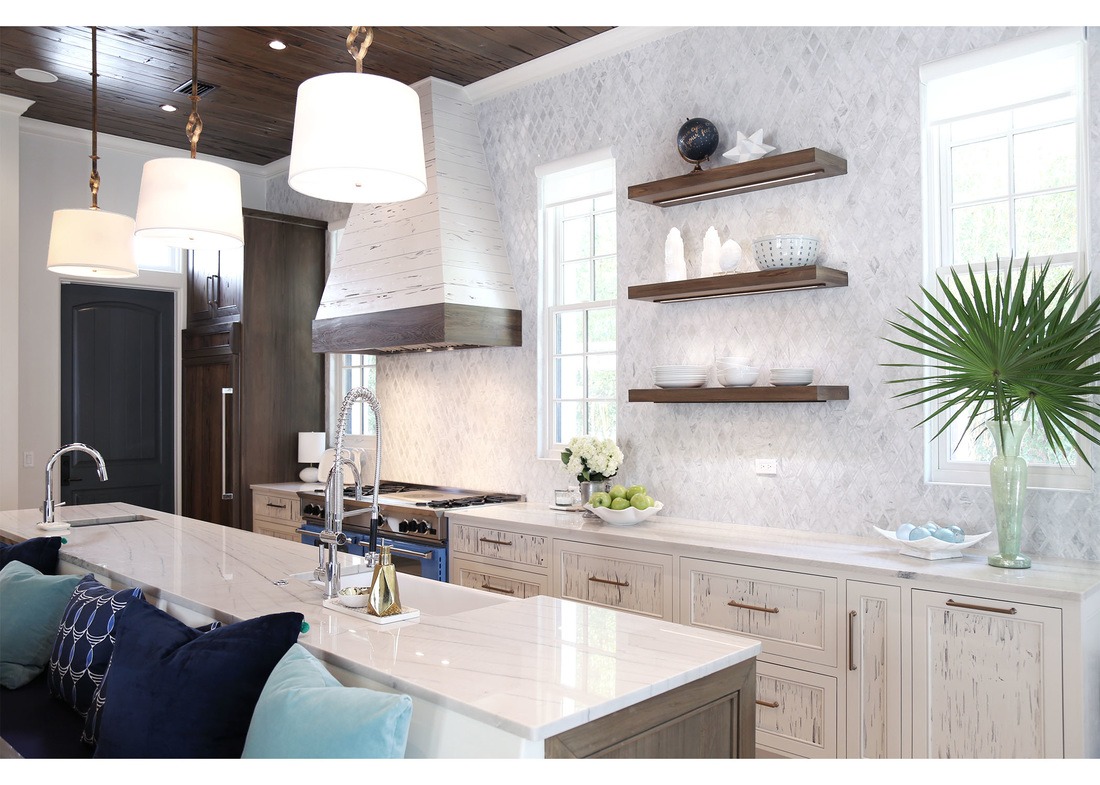 Kitchen designed by Old Sea Grove Homes with stone countertop and backsplash, floating shelves, and drum pendant lights over an island, brass fixtures and a dark wood ceiling