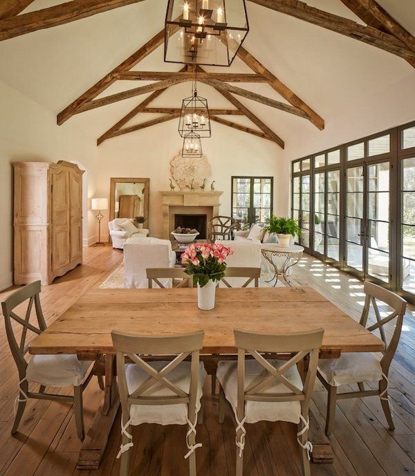 A gabled ceiling with exposed wood trusses over a traditional rustic dining room designed by Thompson Custom Homes