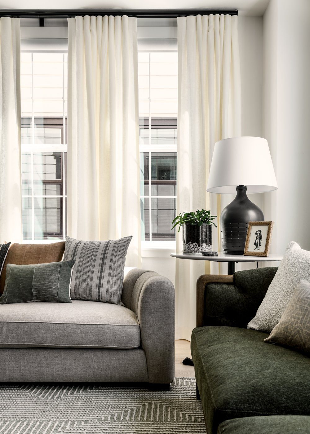Elegant-Simplicity A light gray sofa with three different sized pillows in muted colors with soft patterning, next to a loveseat with two pillows of different colors with textural differences.