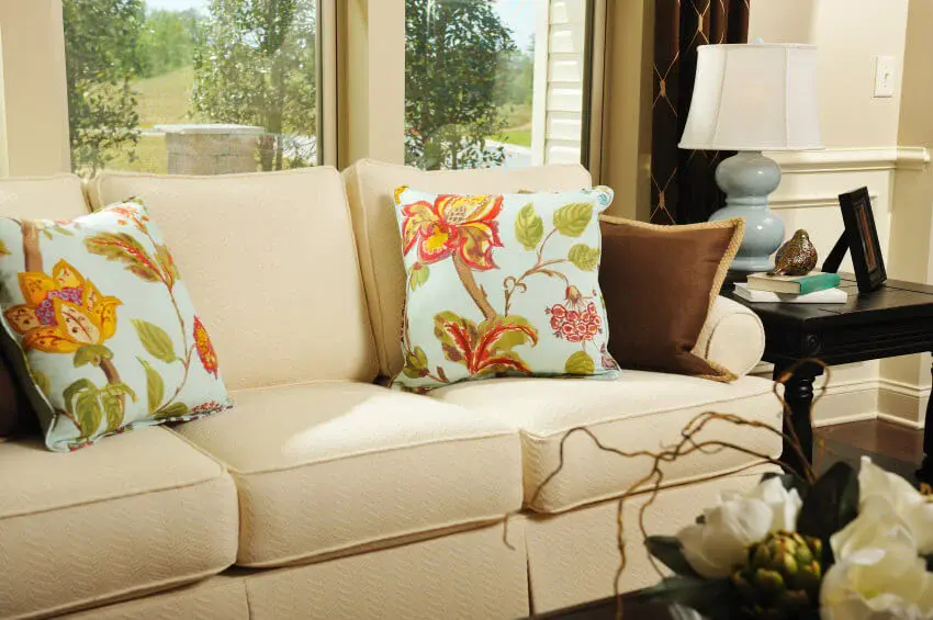 Real Estate photo sofa Neutral creams and browns with a little robins egg blue and a hint of orange in a living room with a sofa and accent pillows.