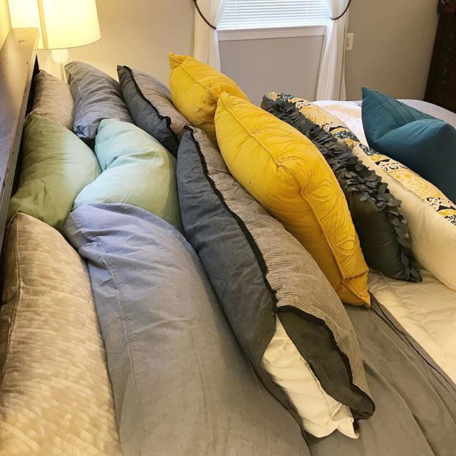 Unknown Author Side Bed Pillows Bed with many plain solid colored pillows stacked in front of each other