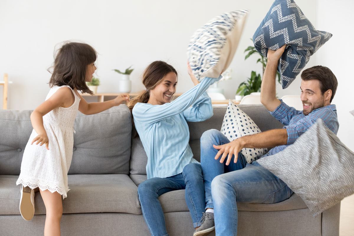 shutterstock_Fizkes-Smaller Young family having a pillow fight on their couch is not a throw pillow mistake