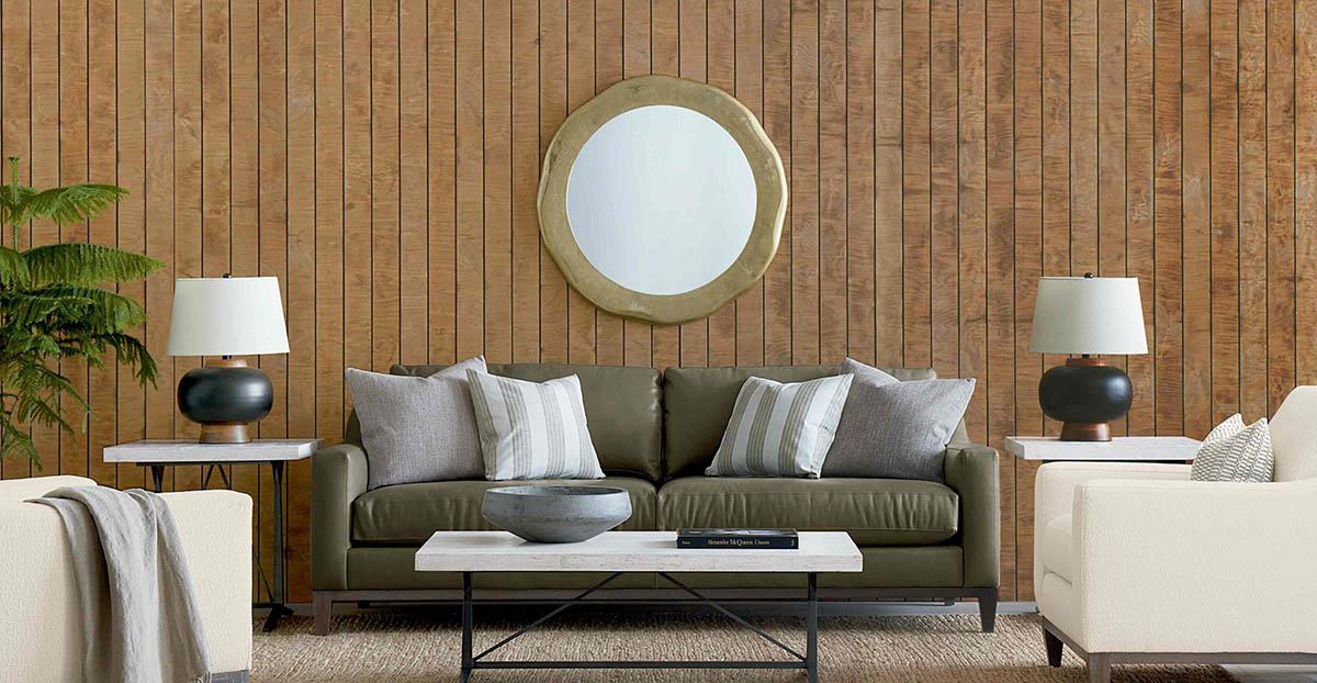 Taupe leather sofa with two sets of matching pillows against the sides of the sofa arms