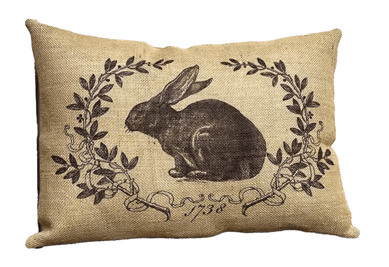 Burlap pillow, rectangular, with drawing of a brown rabbit surrounded by laurel leaves. 