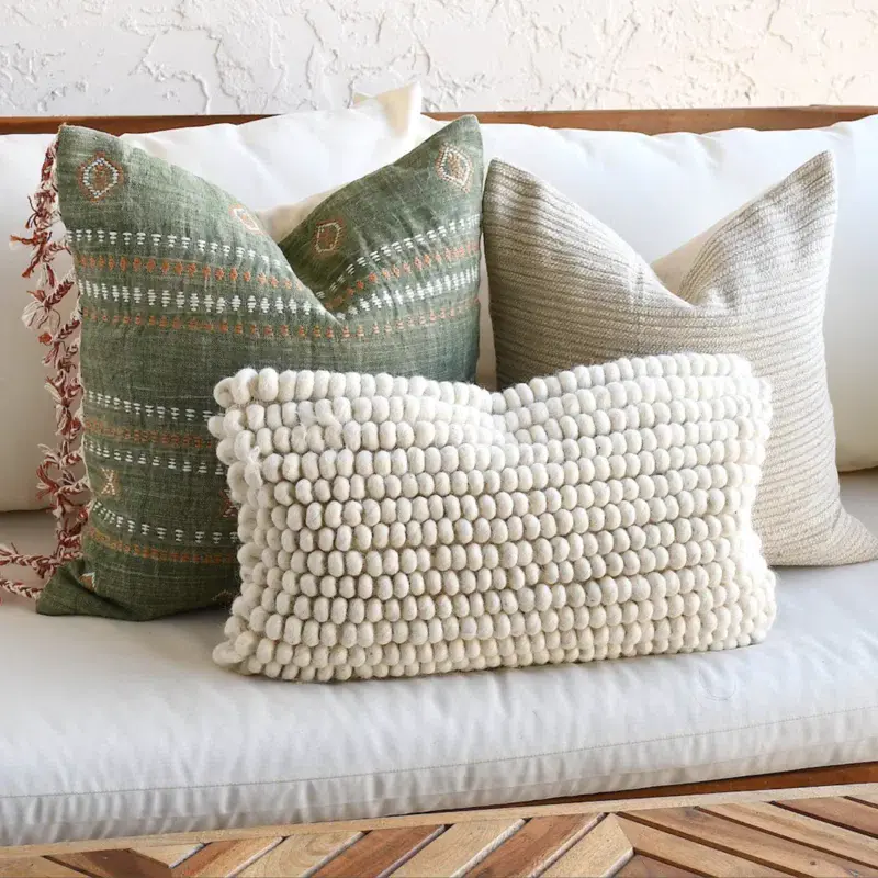 Mulbury+Wool+Blend+Pillow Mulbury Pillow with rows of small cream colored balls made out of wool blend, in front of woven pillow with fringe