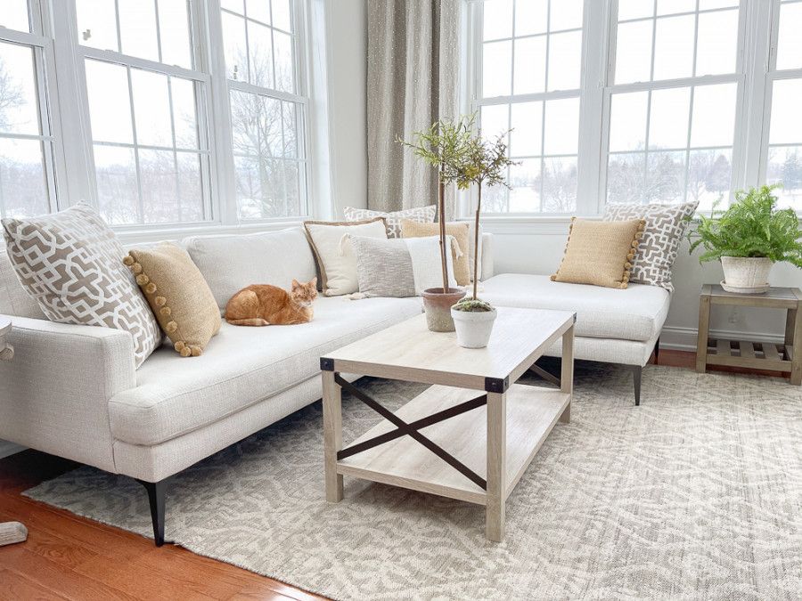 Yvonne at Stone Gable A white chaise sectional with a few pale yellow, taupe and gray toss pillows in soft patterns with texture.