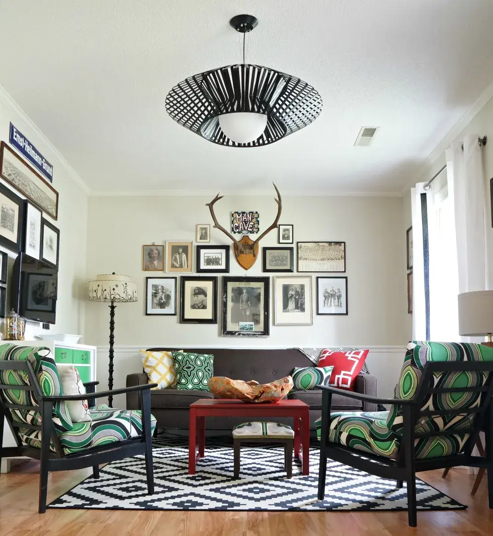 Eclectic living room with patterned armchairs, gallery wall, geometric rug, and bold black lighting fixture.