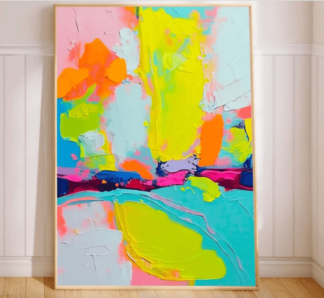 Large abstract painting in bold neon colors including yellow, pink, aqua, and orange, leaning against a white-paneled wall.