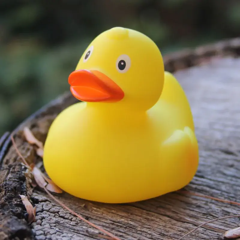 Classic yellow rubber duck with an orange beak sitting on a tree stump.