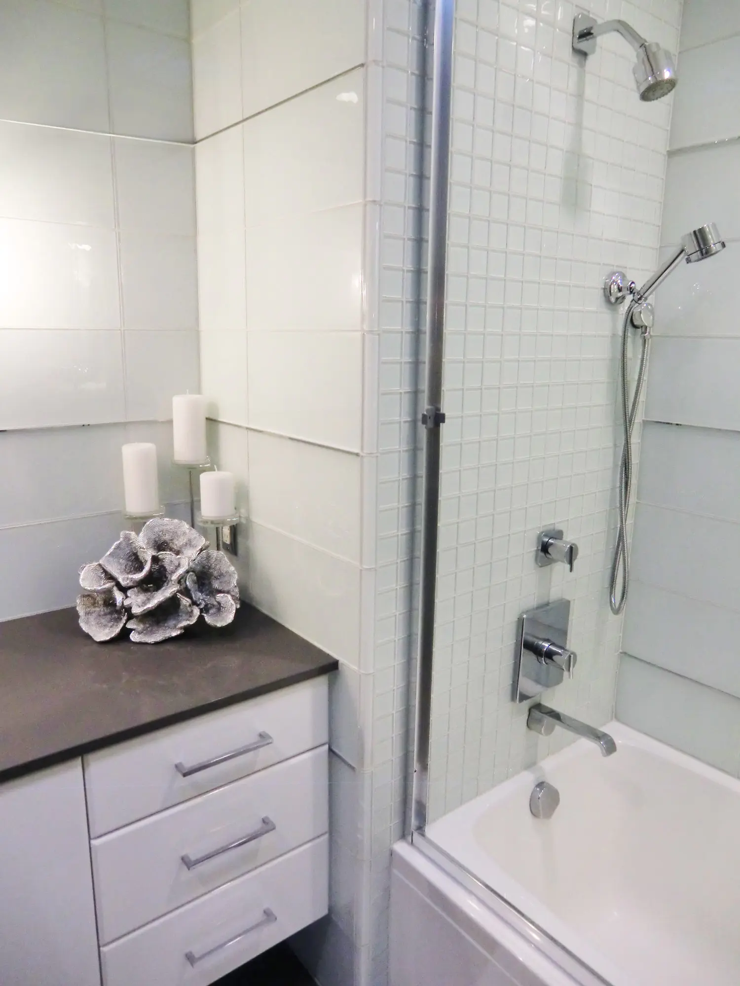 Modern bathroom with white tile shower, glass partition, and dark countertop vanity
