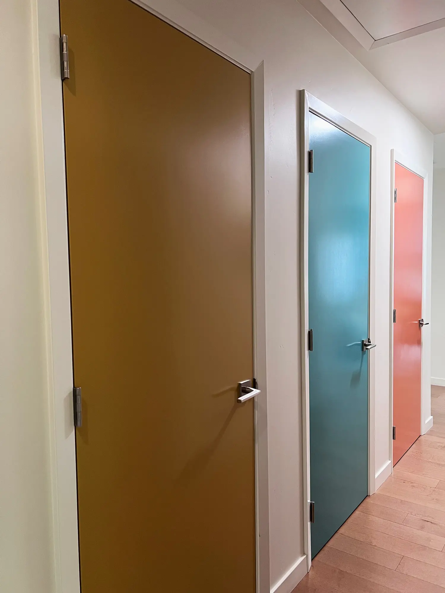 Modern hallway with colorful interior doors in eggplant, teal, and coral
