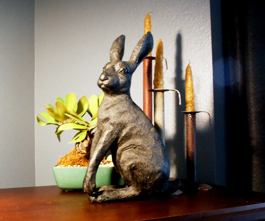 Rabbit sculpture with candles and succulent on wood tabletop