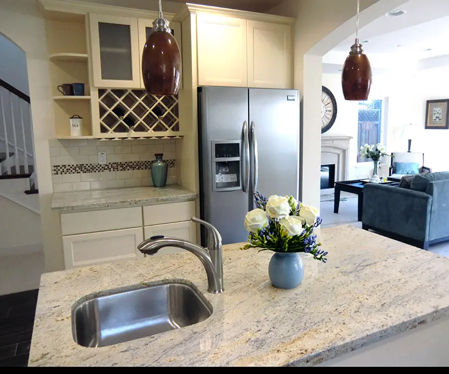 Transitional kitchen with granite island, pendant lighting, custom cabinetry, and open-concept living area.